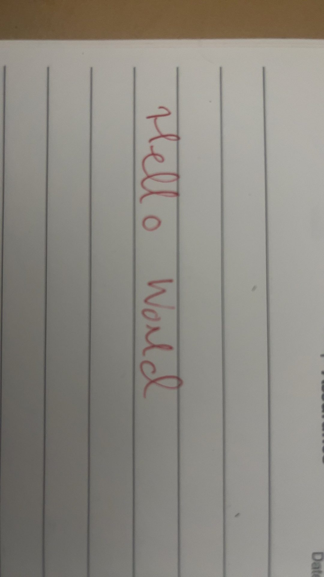 A piece of white lined paper with 'hello world' written in red ink.